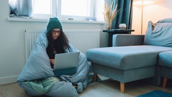 woman wraps up in blanket by her radiator