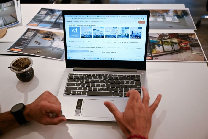 A real estate adviser looks at homes for rent on a laptop