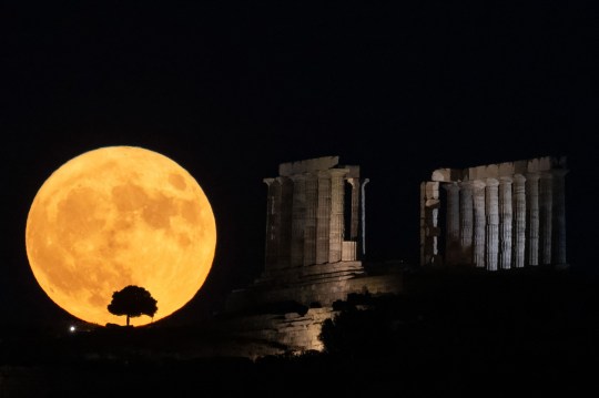 The Sturgeon supermoon rises behind the ancient temple of Poseidon at Cape Sounion