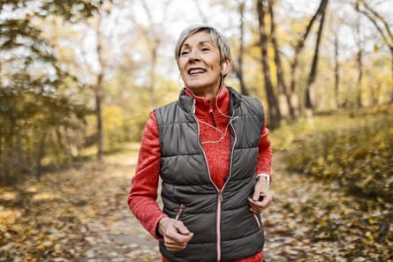 a senior woman jogging on a woodland path