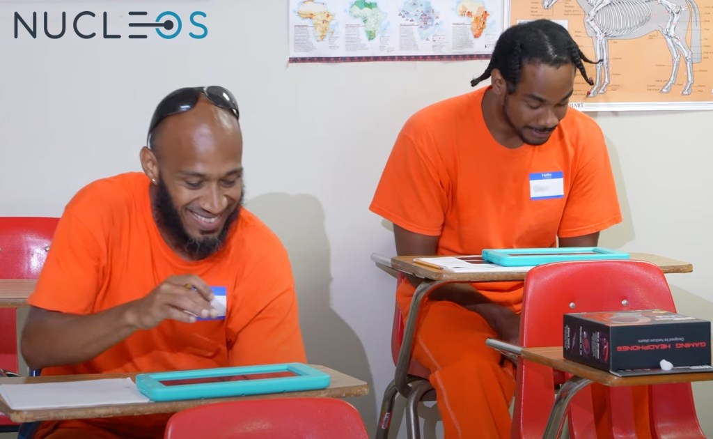 Two inmates use Nucleos tablets in a classroom.