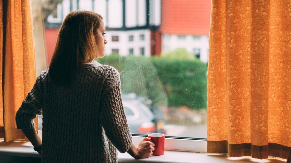 A woman looks out her window