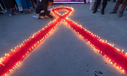 The large red bow of support for Aids/HIV awareness on the ground and bordered with tiny candles.