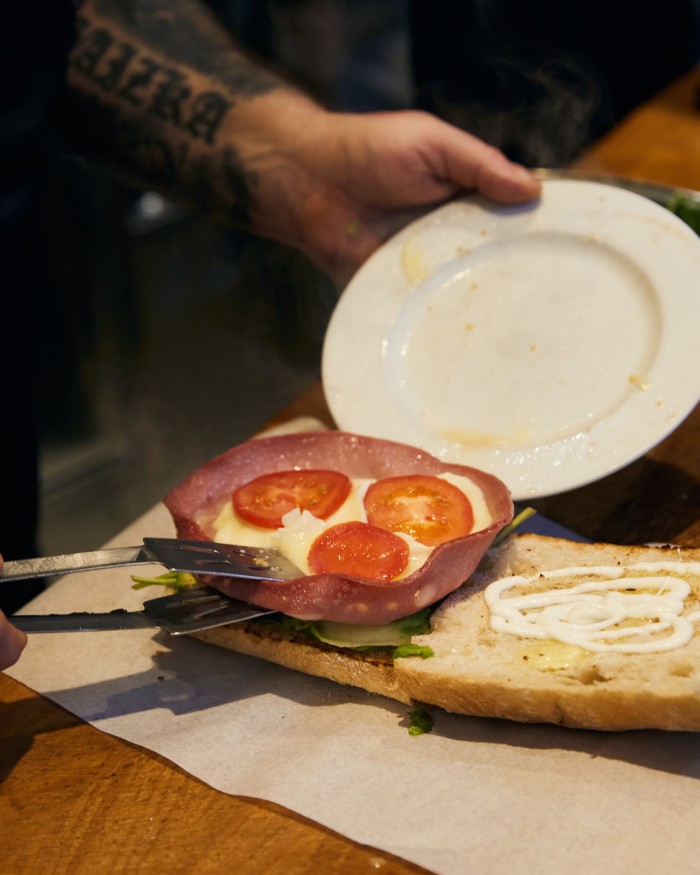 Dilieto’s mortadella Bologna sandwich being placed onto a plate