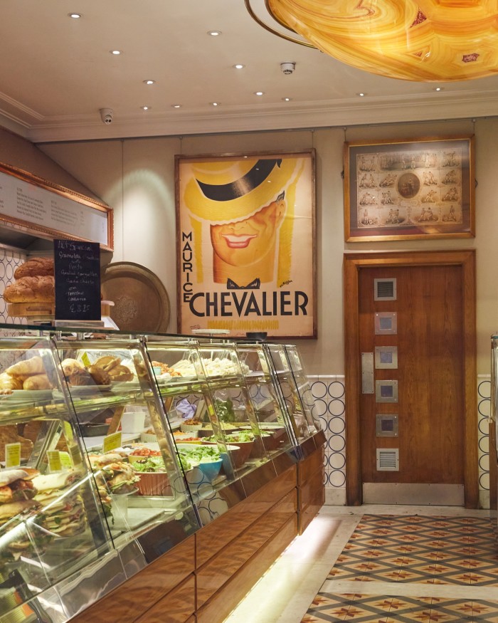 The interior of Birleys on Old Broad Street, with a glass counter filled with sandwiches and a large yellow Maurice Chevalier poster on the wall