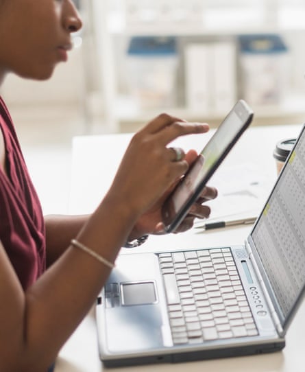 A woman uses a mobile phone and a laptop