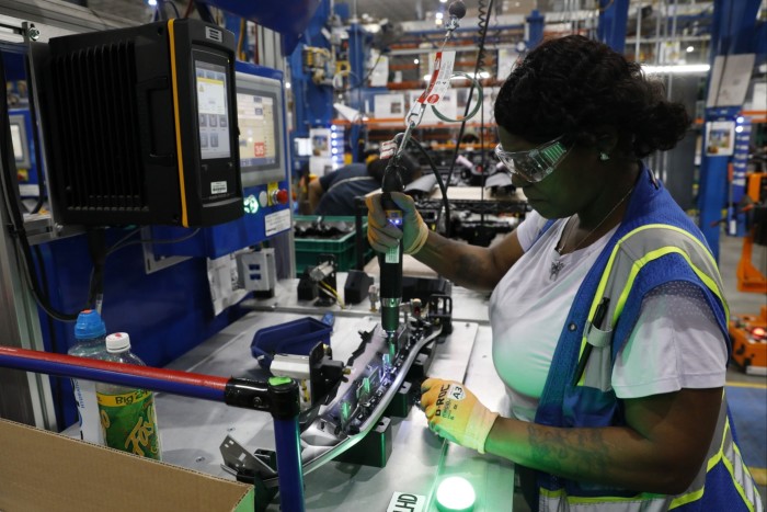 A woman uses a soldering iron to install lights on an instrument panel