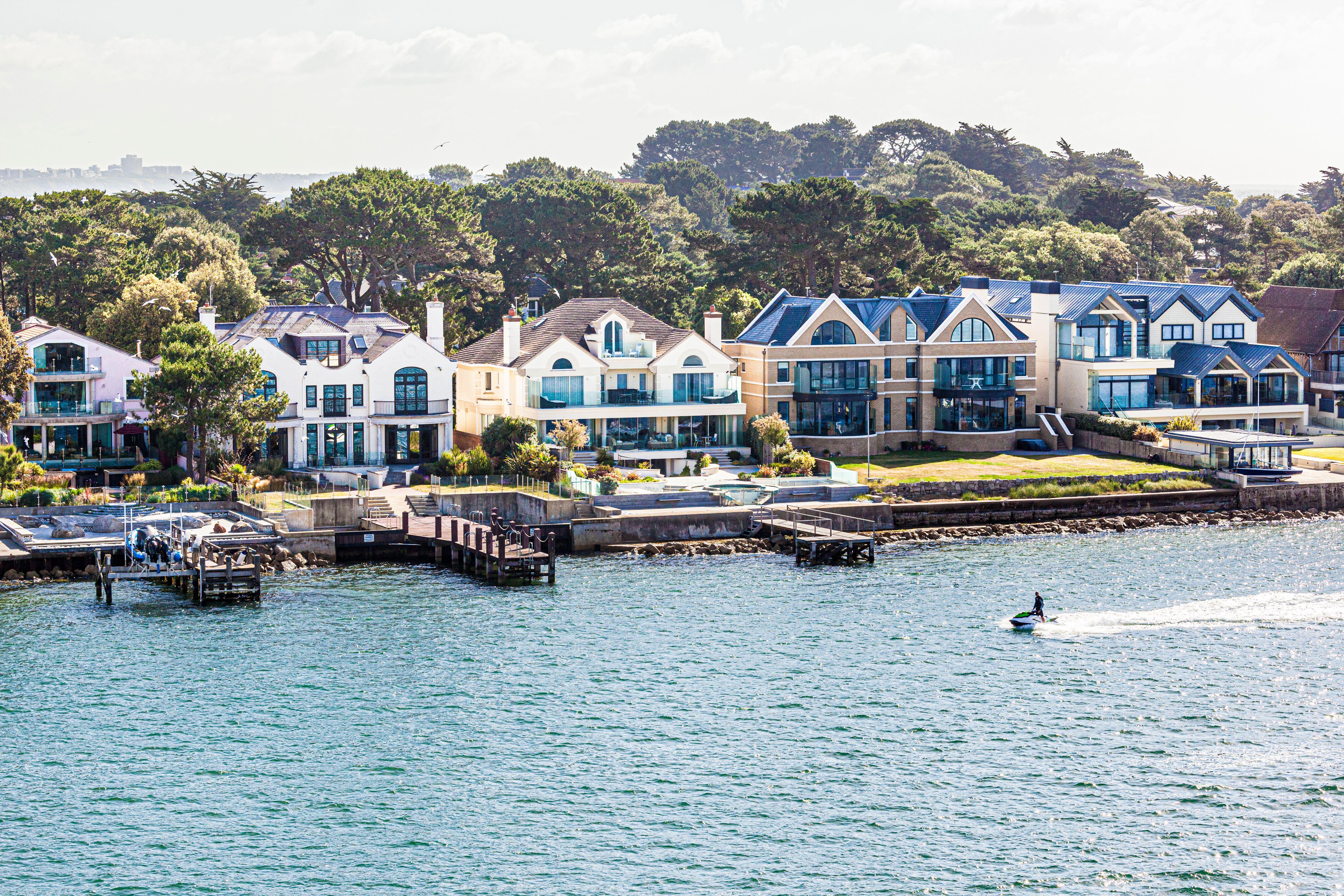 A jetskier passing luxury houses on the Sandbanks Peninsula in Poole Harbour