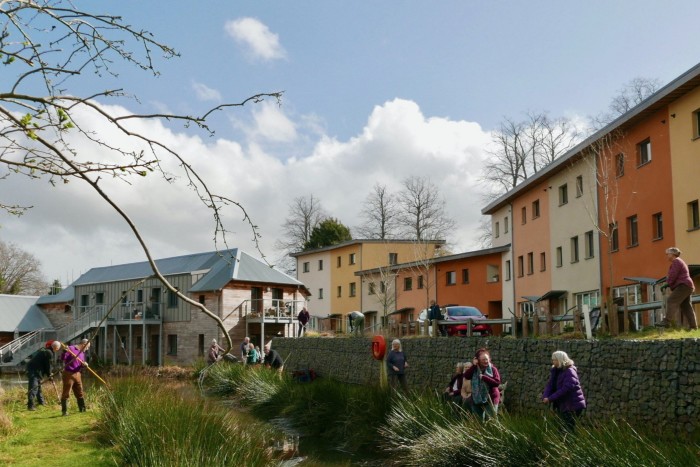 People work by a waterway surrounded by colourful buildings