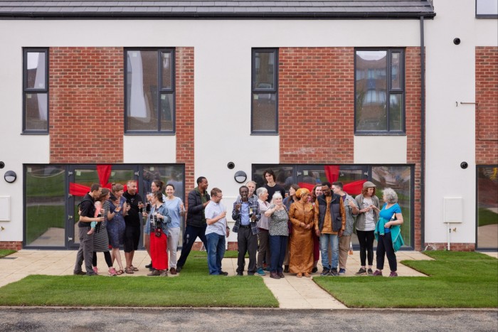 A group of people with champagne toast the new buildings behind them