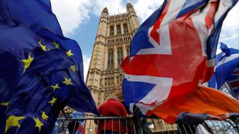 Pro-Brexit and anti-Brexit protesters hold flags as they demonstrate outside the Houses of Parliament in London in 2019