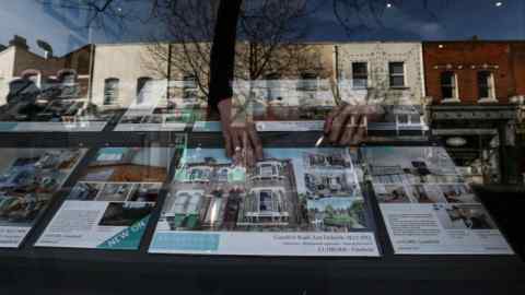 An estate agent adjusts a sign in a display window