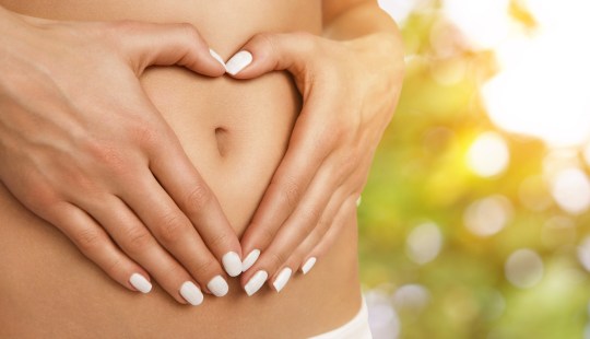 Woman making heart shape with hands around her bellybutton