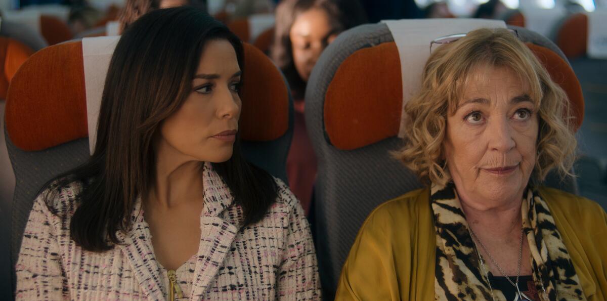 Two women sitting in seats on a plane.