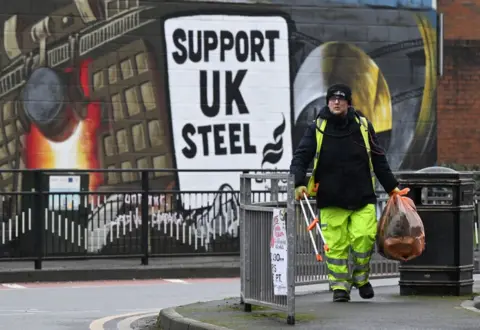 Getty Images A rubbish collector walks past a mural in support of the UK Steel near to the Port Talbot steelworks
