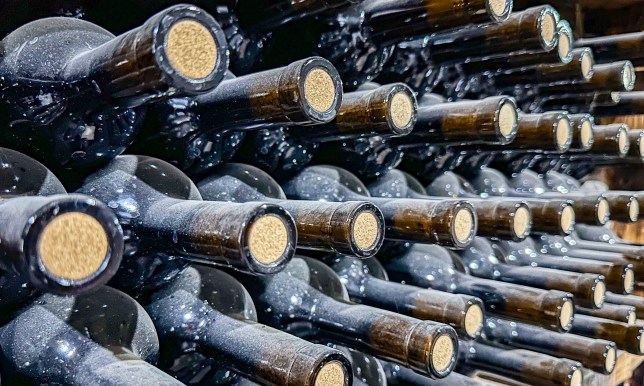 Old wine cellar with corked bottles heaps in dust