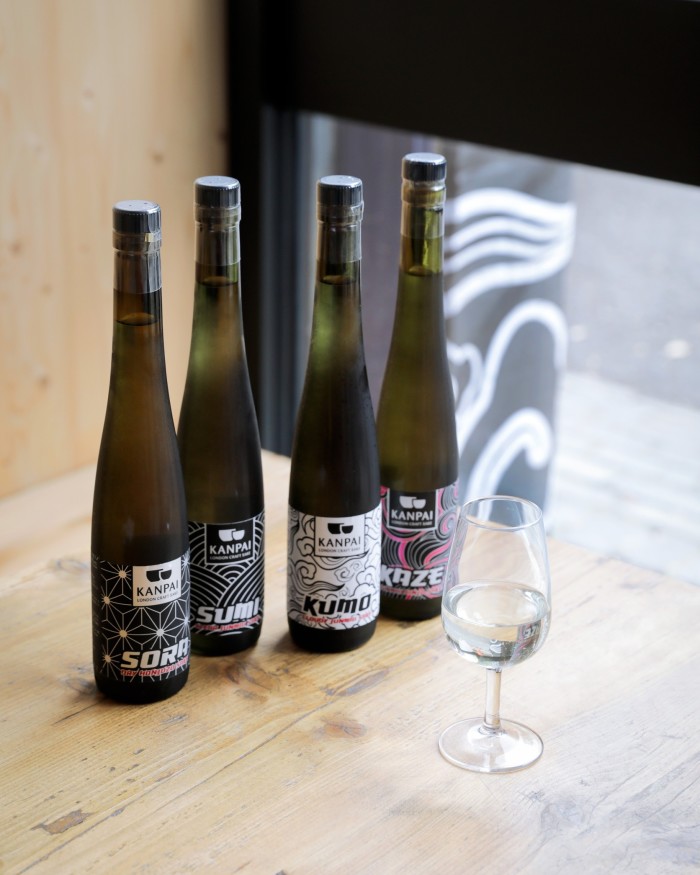 Four of Kanpai’s bottles of sake in front of a glass of sake 