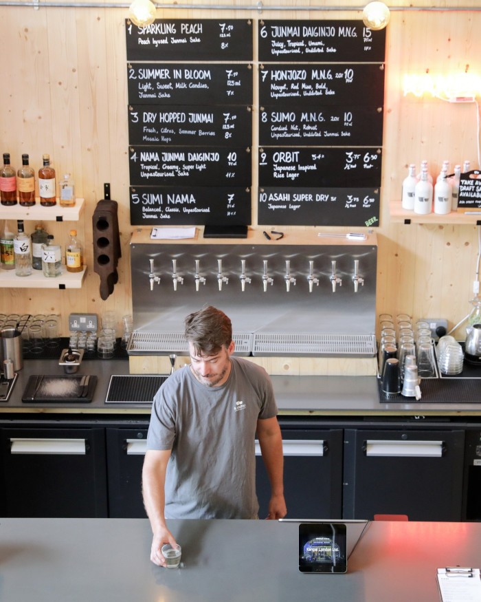 Kanpai co-founder Tom Wilson placing a glass of sake on a counter