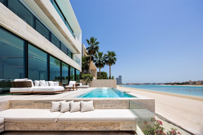 Sleek white concrete home, outdoor divan with cushions and lap pool right on the beach