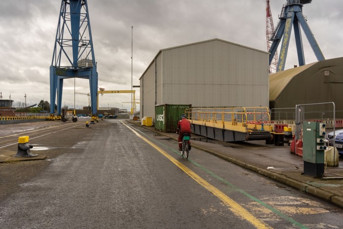 A worker cycles by the dry docks at Harland & Wolff  in Belfast