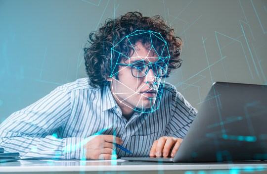 Business man at computer with face being scanned