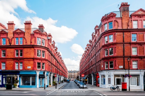 A symmetrical view of two large, red-brick buildings on either side of a narrow road