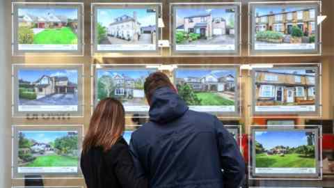 A couple looking at properties in an estate agent’s window