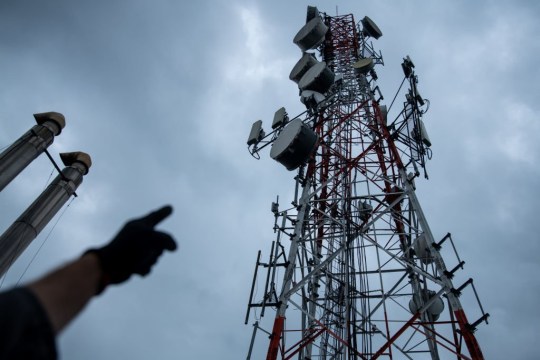 A worker points to a telecommunications tower, including 5G antennas, at Claro's operations center in Cali, Colombia