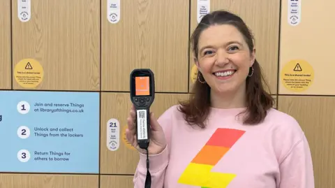 Library of Things Heather Mullin in a pink jumper holds up a thermal camera