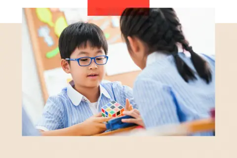 Getty Images Two children in school uniform play with a colourful puzzle cube