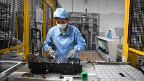 A worker assembles an electric car battery inside a factory